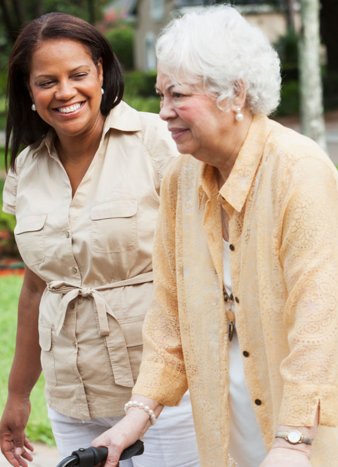 A young lady walking beside an elderly lady with walker